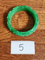 Top-down photo showing the round shape and the detailed carvings of the green jade bracelet.