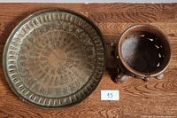 Decorative brass bowl next to wooden footed bowl on hardwood floor
