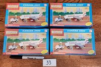 Four boxed Best Lock Canada 3000 construction toy sets on wooden surface with a marker and lot number card.