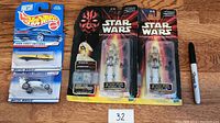 Lot contents on wooden floor with Sharpie for scale, showing two sealed Hot Wheels cars and two sealed Star Wars Episode I action figures.