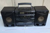 Full front view of Sony CFD-560 unit flanked by two speakers on either side, showing the overall condition and setup