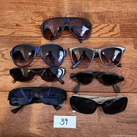 Top view showing all 7 sunglasses laid out on wooden surface