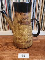 Front angled view of vintage artisan jug showing textured body, spout, and handle.