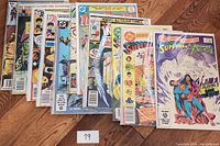 Full spread of 11 vintage comic books showing front covers, mostly DC Comics titles with colorful covers describing storylines, including Superman variants.