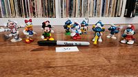 Front view of all 11 toy figures displayed in a row with a Sharpie marker for size reference