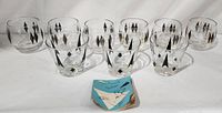 Set of nine clear glass tumblers with black and gold diamond pattern arranged in two rows with 'Smart Hostess' booklet placed in front on white background. Shows overall lot contents and condition.