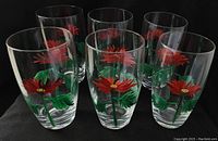 Front view of all six glass cups arranged closely together showing hand-painted red flower design with green leaves on each.