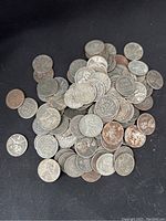 Close-up photo showing a pile of steel wheat pennies with visible wheat ears on the reverse sides and Lincoln profile on obverse sides.