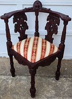 Front view showing the wooden chair with mahogany stain, carved intricate details, and reupholstered seat with red and beige striped floral pattern.