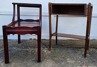Side view of two side tables: dark wood step table with scalloped shelves and gold accents, and a lighter wood Danish modern style side table with an open drawer and lower shelf