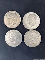 Four used US Eisenhower one dollar coins showing obverse with Eisenhower profiles dated 1972, two 1776-1976 bicentennial, and 1978.