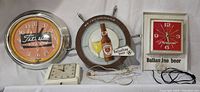 Four vintage clocks and bar light including Ballantine beer lighted bar clock with pendulum, schooner wheel shaped clock with bottle and goblets, Titleist Staff neon bar clock, and small Telechron electric clock.