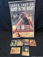 Photo showing Godzilla poster with six vintage space-themed trading cards placed in front of it.