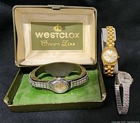 Four vintage women's watches shown, including a Westclox watch in original green box and three watches with metal bracelets, one gold-tone, others silver-tone.