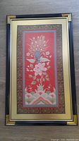 Front view of antique Chinese embroidery artwork framed in gold and black wooden frame.
