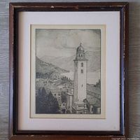 Full view of framed etching of tower and landscape, showing slight wear on wooden frame and cream mat.