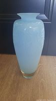 Front view of opaque blue studio art glass vase with flared rim and abstract design on surface.