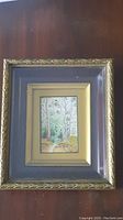 Framed miniature watercolour painting showing whole frame with dark wood surface background
