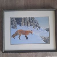 Frontal view of the painting showing red fox in snow beside rocky ridge, framed and matted.