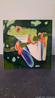 Full front view of the colorful ceramic tile showing a frog on a branch with signature and good overall condition.