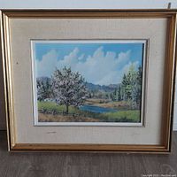 Framed landscape oil painting showing overall view of the artwork including frame and matting.