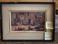 Front view of framed artwork showing village street scene with women and children