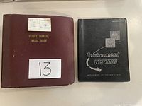 Photo showing the red leather Flight Manual Basic Book and black softcover Instrument Flying Manual side by side on a table.