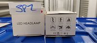 Photo of two white boxes for LED headlamps showing usage icons for cycling, mountaineering, night fishing, camping, and running.