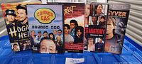 Photo showing five DVD cases lined up side by side: Hogan's Heroes The Complete Series, Corner Gas Season One, 21 Jump Street, Grey's Anatomy Season One, and MacGyver Season Six.