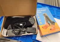 Top view of open box containing black and gray heated socks with charging cables and adapters alongside product packaging box.
