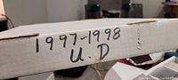 Side view of the white storage box showing handwritten label '1997-1998 U.D.' indicating the contents as Upper Deck hockey cards from that season.