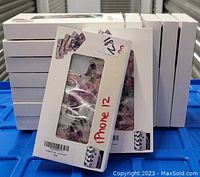 Stack of 13 individual retail boxes containing the floral design iPhone 12 cases, each box with a clear window showing the flower pattern on the case.