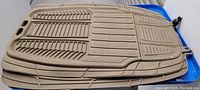 Two beige Michelin car floor mats stacked, showing textured surface and connector holes.