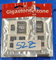 Two sealed Gigastone branded packages, each containing five 16GB micro SD cards and five corresponding adapters, displayed on a blue surface with handwritten label '52Z'.
