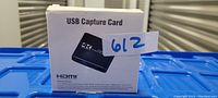 Photo of boxed USB capture card with 4K HDMI label, barcode, and model details.