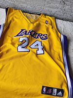 Front view of yellow Kobe Bryant Los Angeles Lakers basketball jersey with number 24 and logos.