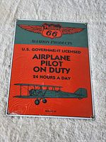 Front view of metal sign showing Phillips 66 logo, text, and airplane graphic with protective wrapping still on.