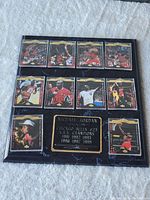 Image showing a black marble-effect plaque with ten Michael Jordan basketball cards and a central gold engraved plate listing Chicago Bulls NBA championship years.