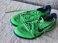 Side angle view showing bright green mesh upper, black Nike swoosh, and the overall shape of the sneakers.