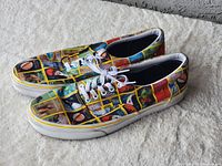 Pair of Vans sneakers with colorful National Geographic magazine cover prints, showing the side and top views.