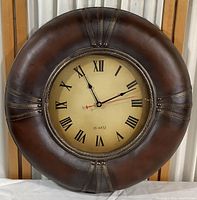 Front view of the leather bound quartz wall clock showing the entire circular clock face and leather trim.