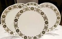 Six Johnson Brothers Snow White Malaga pattern dinner plates arranged upright on stands, showing detailed medallion border design.