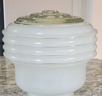 Side view showing ribbed white glass body with smooth taper and clear concentric ribbed glass top.