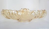 Side view of oblong amber glass bowl showing scalloped edges and petal ridge pattern