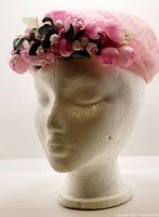 Front view of pink vintage hat on mannequin showing floral cluster and netting