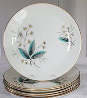 Set of six vintage dinner plates stacked and shown with one upright to display pattern and gold rim