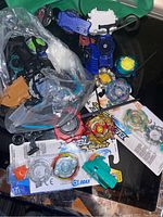 Overview of the lot showing multiple Beyblade Burst tops, launchers, ripcords, and packaging spread out on a surface.