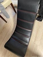 Top view of the gaming chair showing black leather surface with red horizontal stitching.