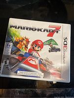 Close-up photo of the Mario Kart 7 game case for Nintendo 3DS showing cover art and ratings.