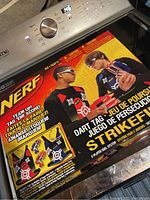 Photo of the Nerf Dart Tag Strikefire set in its original sealed box showing artwork of two children playing, Nerf guns in red and blue, and box text.